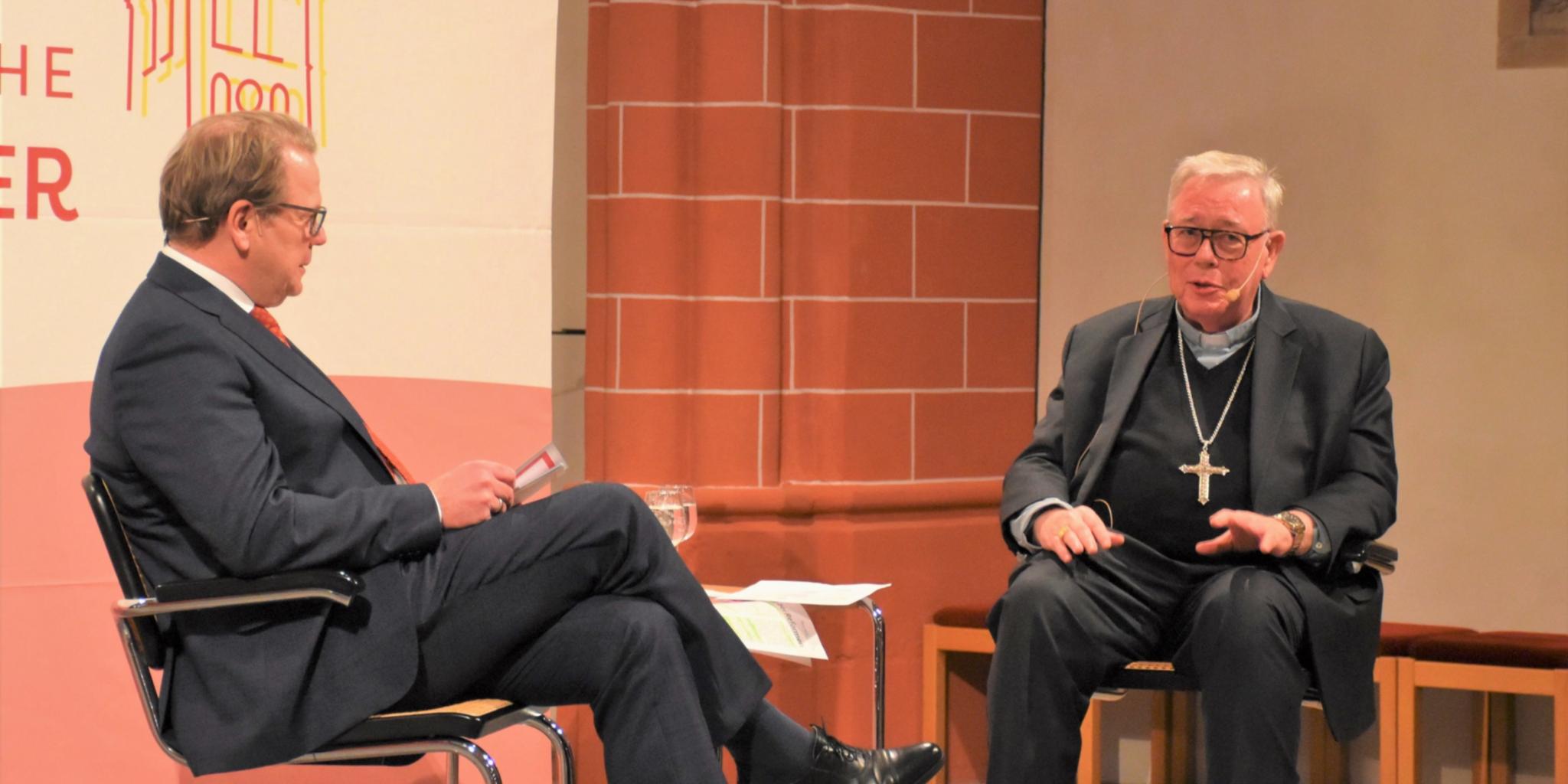 Zwei Männer sitzen auf einer Bühne und unterhalten sich