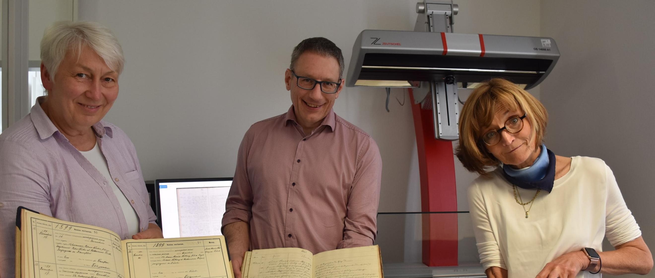 Drei der 7000 Kirchenbücher aus dem Bistum, die im Projekt digitalisiert werden, zeigen Monica Sinderhauf, Stefan Nicolay und Marita Kohl (von links).