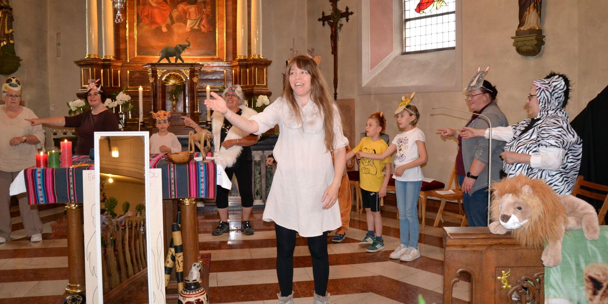 Eine Frau steht vor einem Altar und singt, drumherum Kinder in Tierkostümen (c) Dieter Ackermann Eine Frau steht vor einem Altar und singt, drumherum Kinder in Tierkostümen