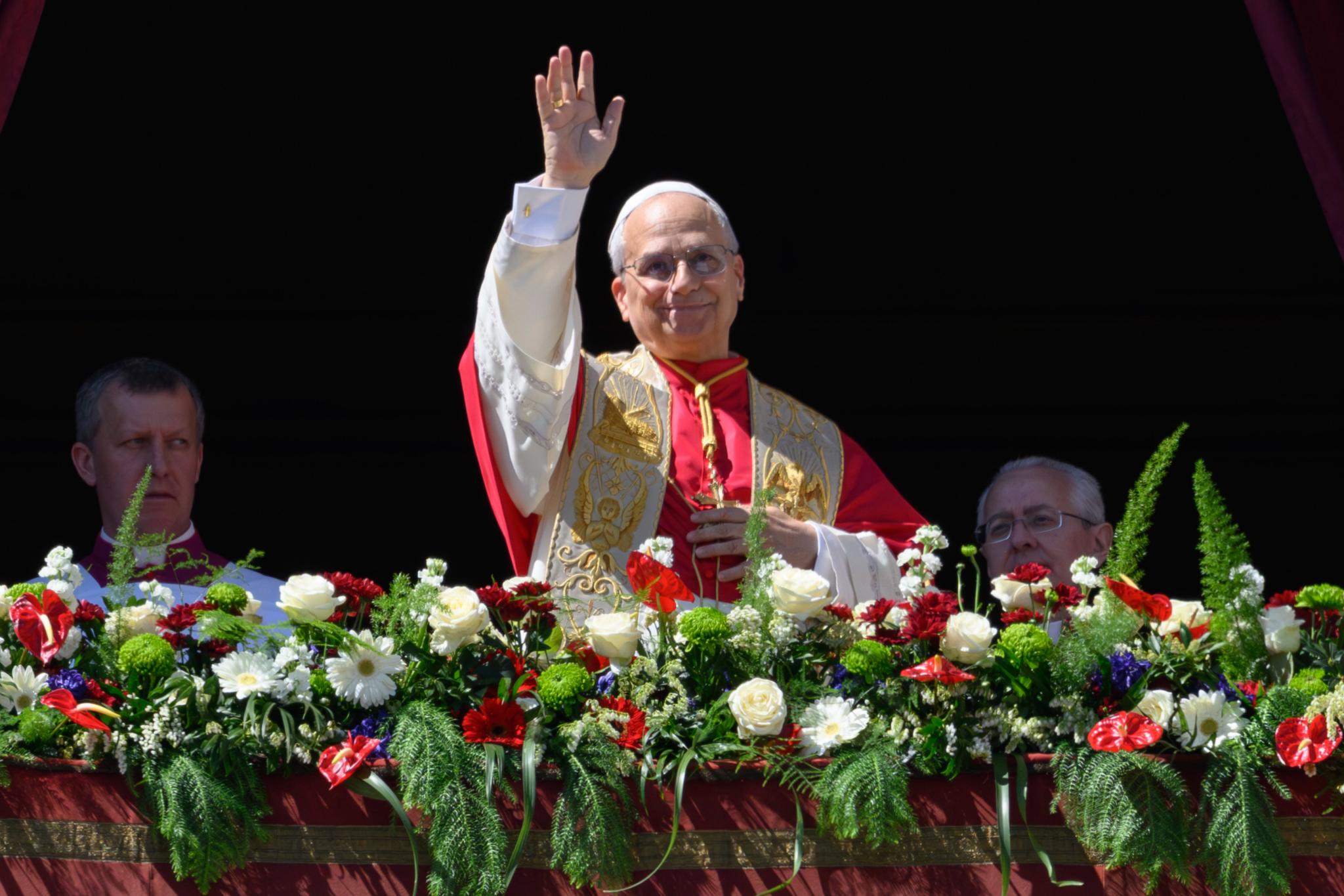 Ein Mann winkt von einem mit Blumen geschmückten Balkon