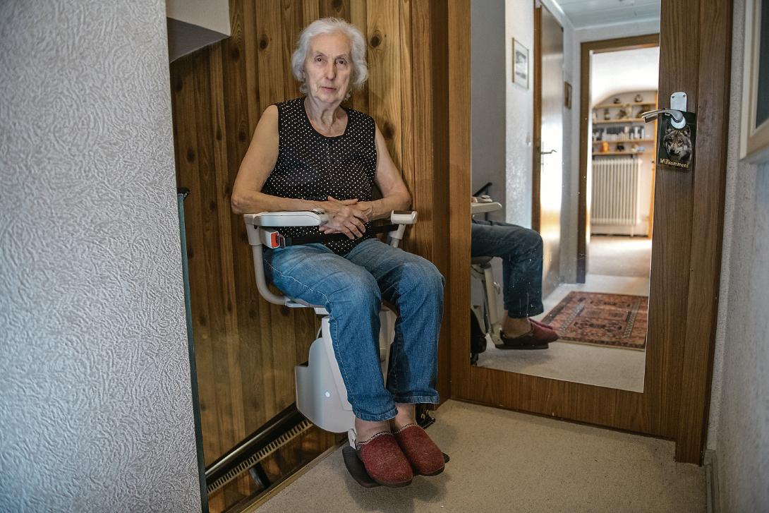 Eine Frau sitzt auf einem Treppenlift.