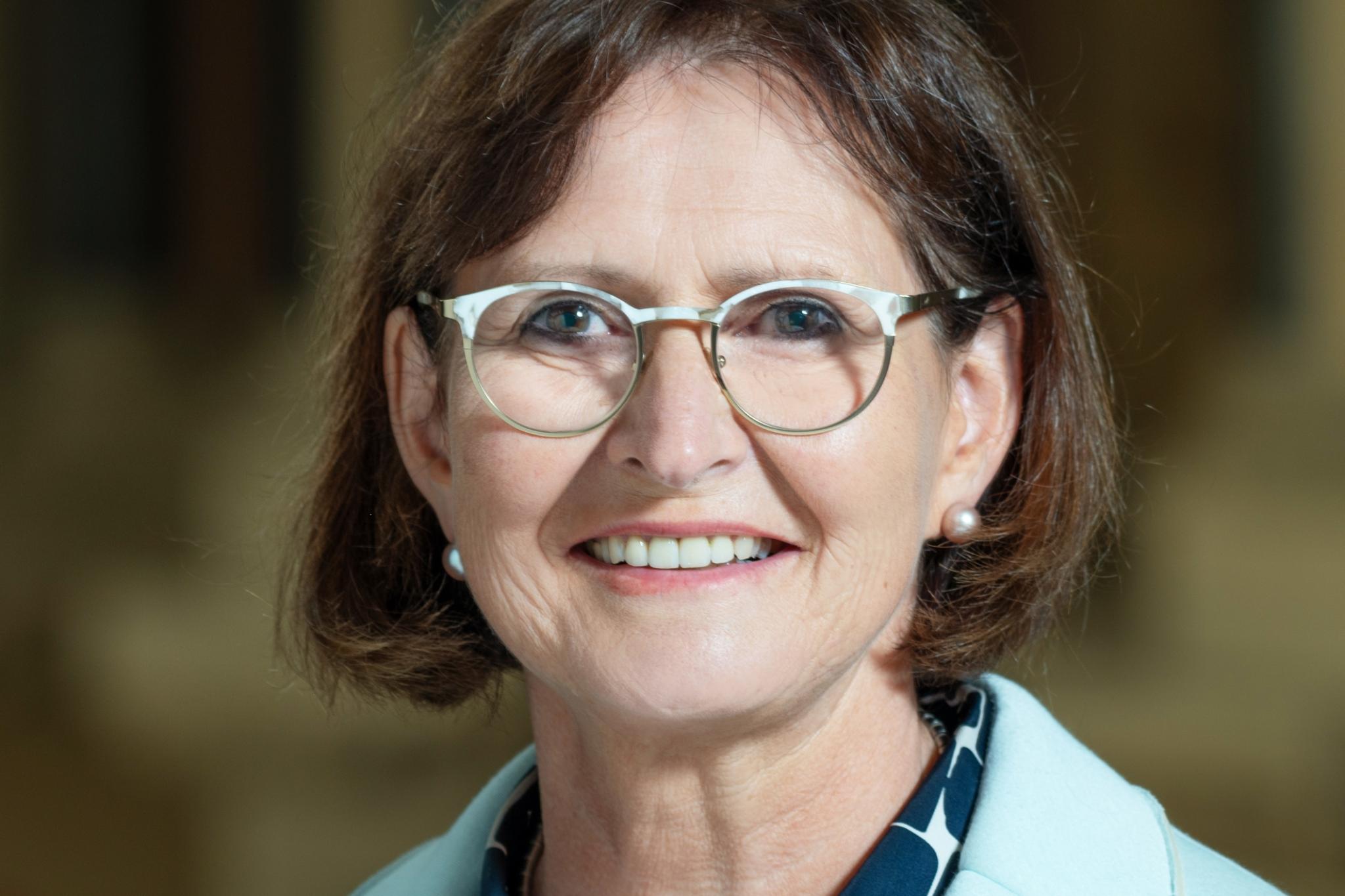 Eine Frau mit Brille und kurzen Haaren lächelt in die Kamera