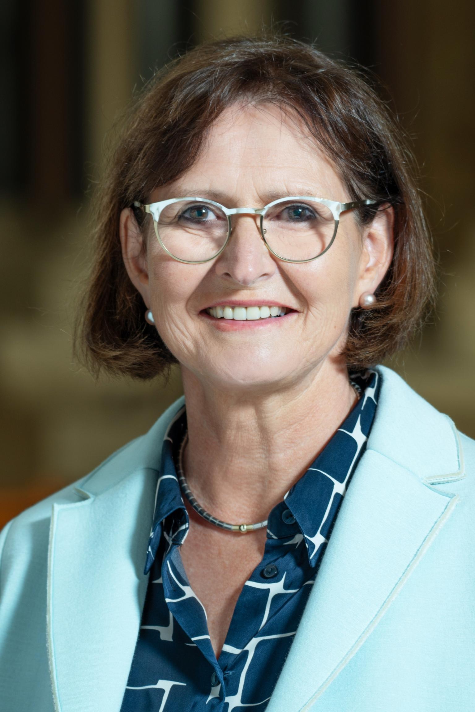 Eine Frau mit Brille und kurzen Haaren lächelt in die Kamera