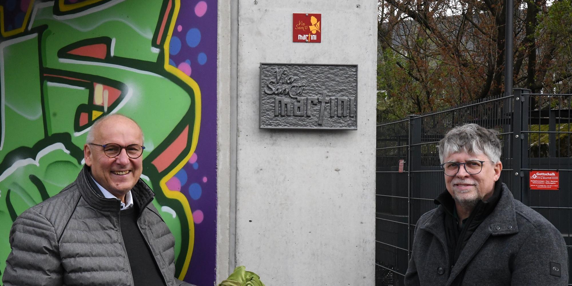 Horst Drach (links) und Andreas Wagner präsentieren die frisch enthüllte Wegmarke und die Plakette zum Martinusweg.