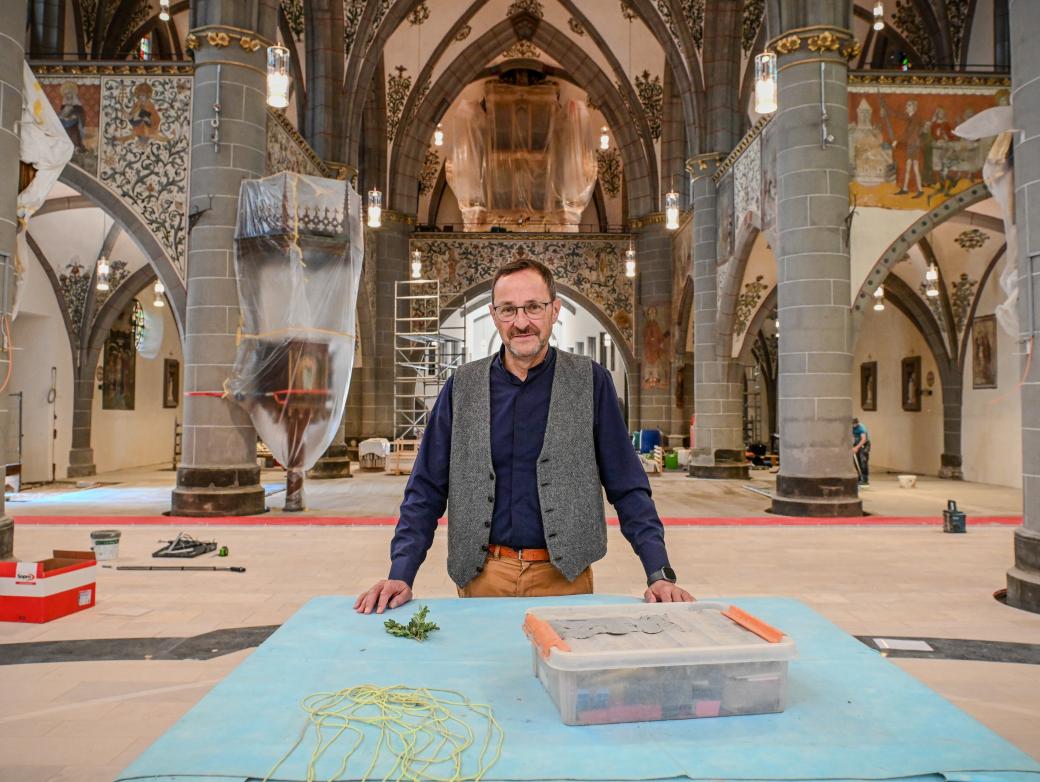 Ein Mann steht in einer Kirche, in der viele Abdeckplanen liegen