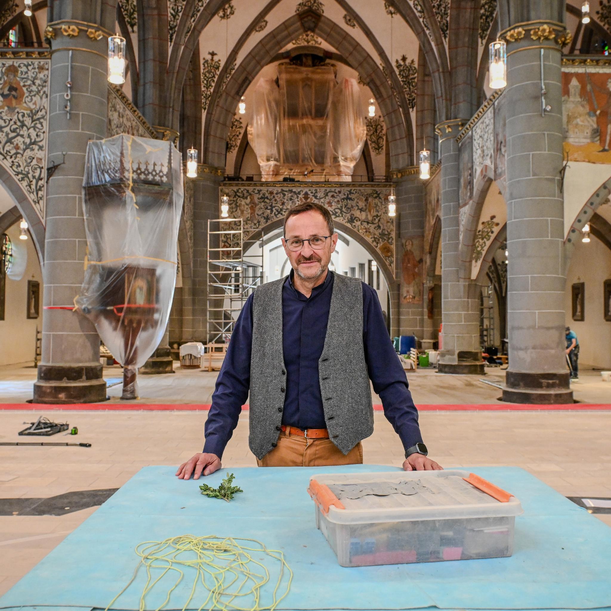 Ein Mann steht in einer Kirche, in der viele Abdeckplanen liegen