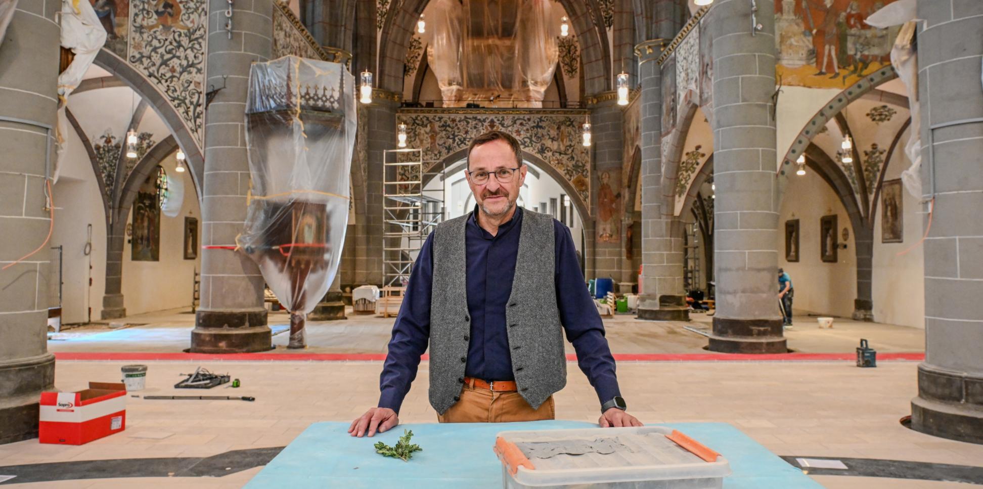 Ein Mann steht in einer Kirche, in der viele Abdeckplanen liegen