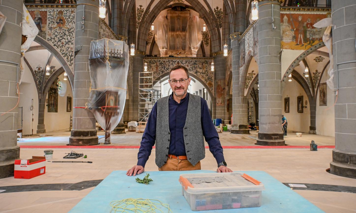 Ein Mann steht in einer Kirche, in der viele Abdeckplanen liegen