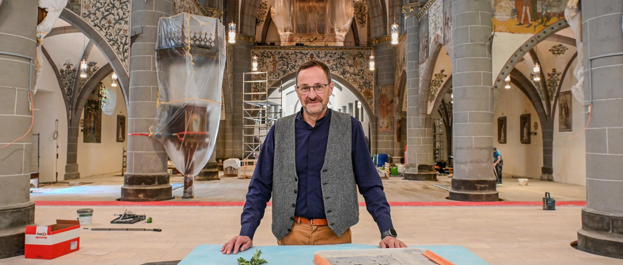 Ein Mann steht in einer Kirche, in der viele Abdeckplanen liegen