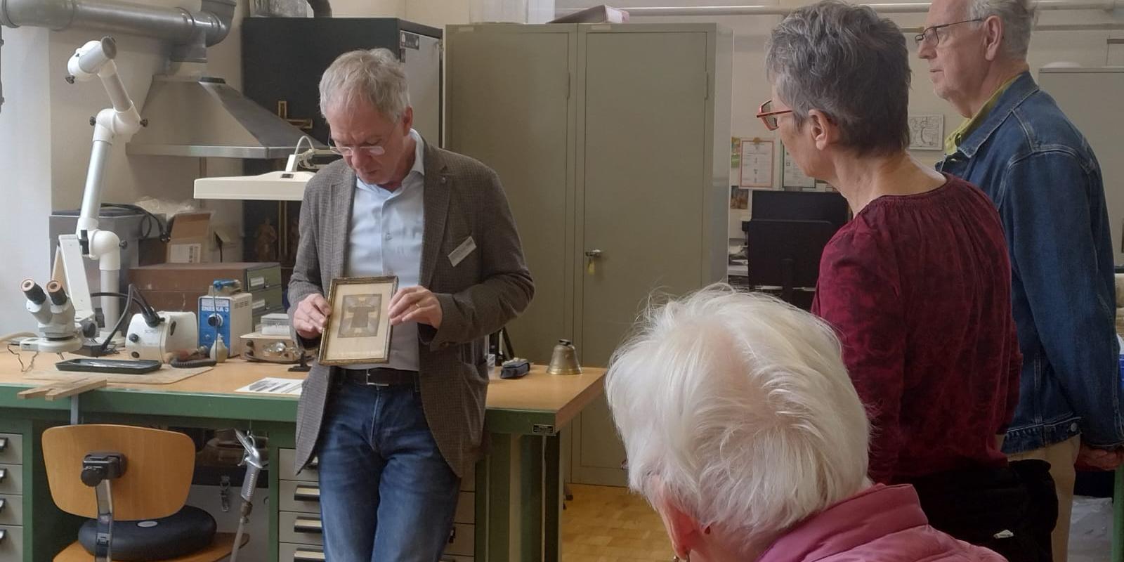 Der stellvertretende Museumsleiter und Restaurator Stefan Schu zeigt Gästen ein gerahmtes Bild. (c) Julia Hansjosten Der stellvertretende Museumsleiter und Restaurator Stefan Schu zeigt Gästen ein gerahmtes Bild.
