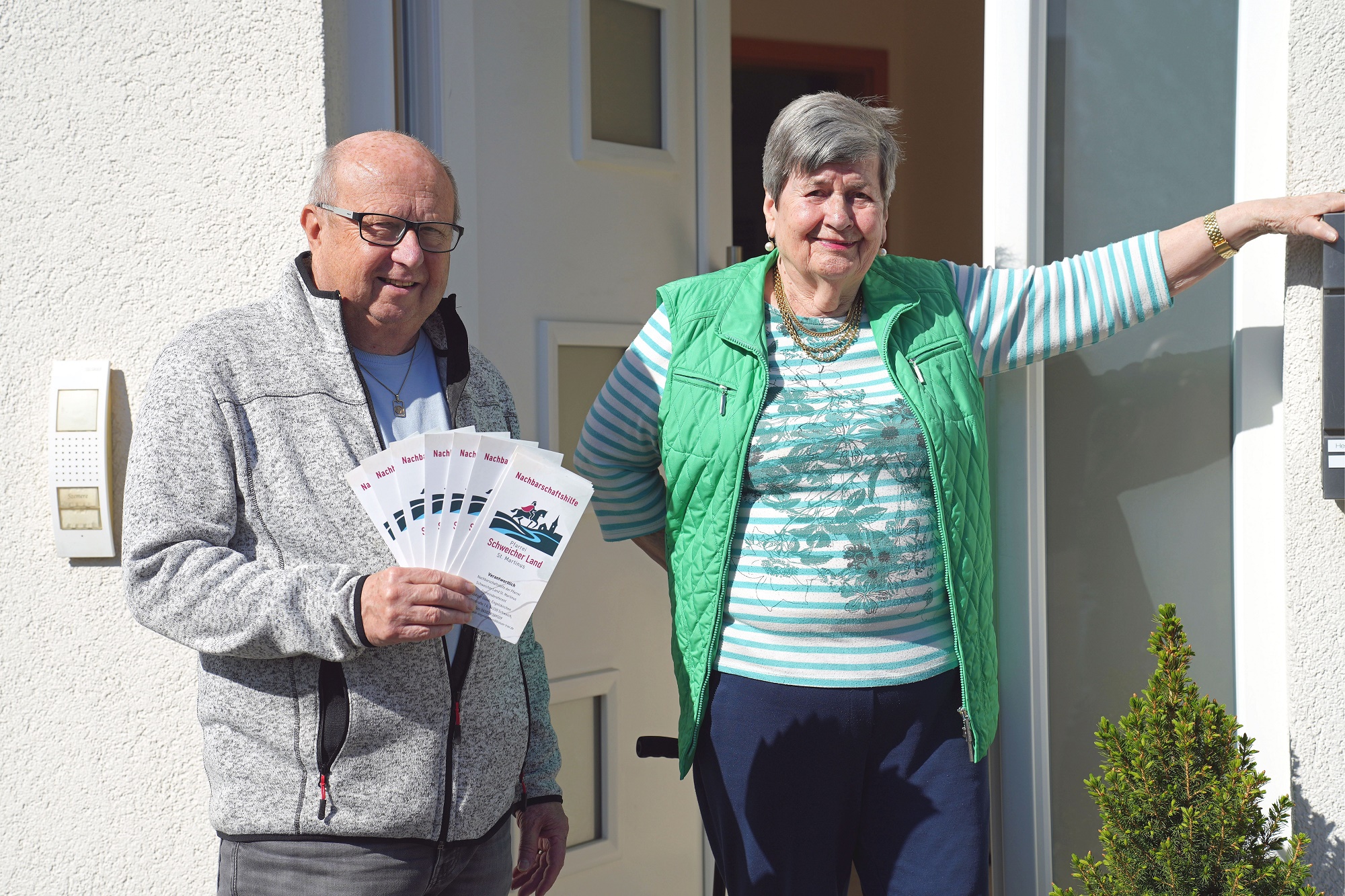 Bruno Christmann mit Flyern in der Hand steht zusammen mit Elfride Heim-Idselis in der offenen Haustüre.