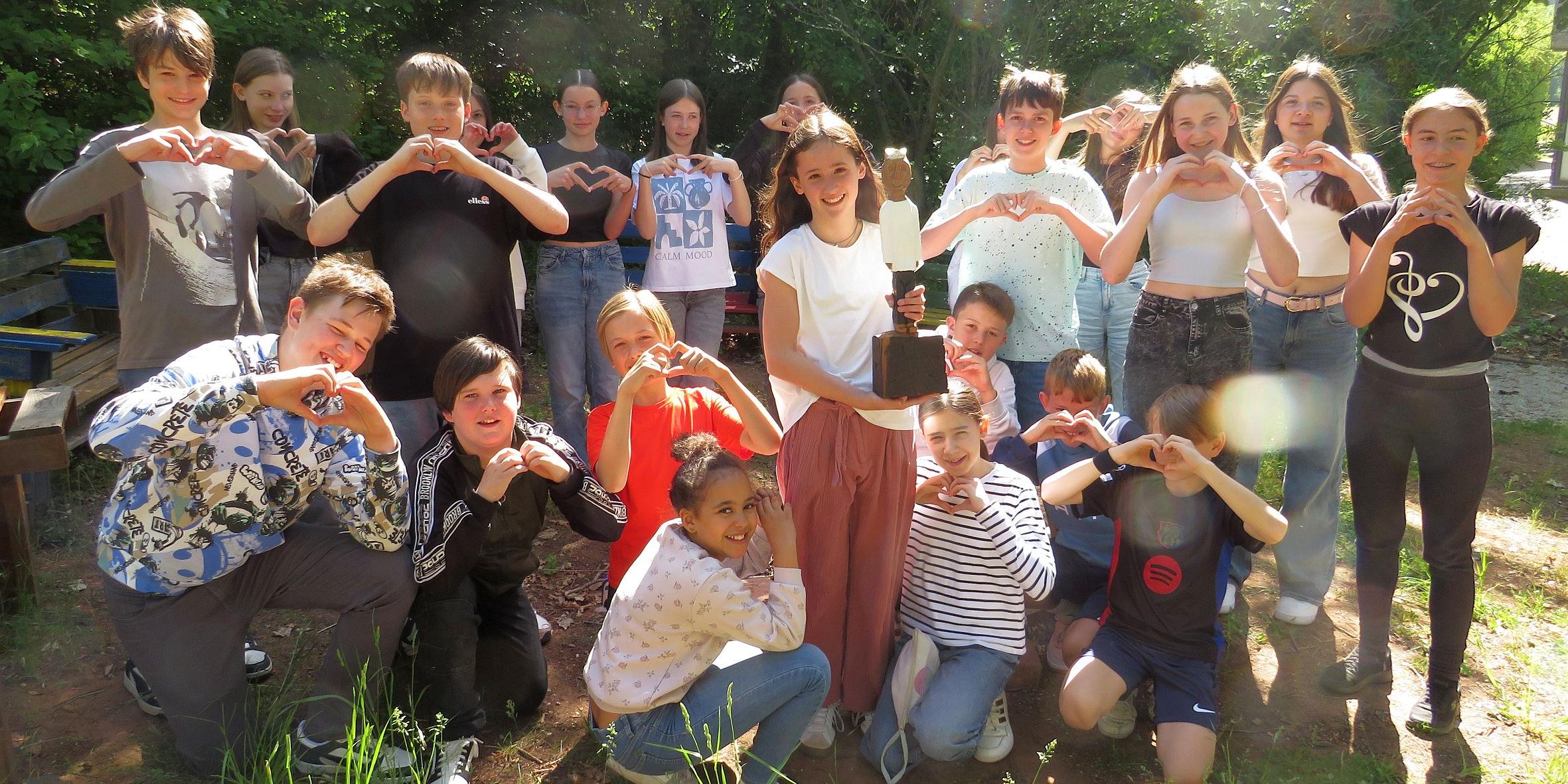 Eine Gruppe Schüler formt mit den Händen ein Herz, in der Mitte eine Königsfigur (c) Claudia Römer Eine Gruppe Schüler formt mit den Händen ein Herz, in der Mitte eine Königsfigur