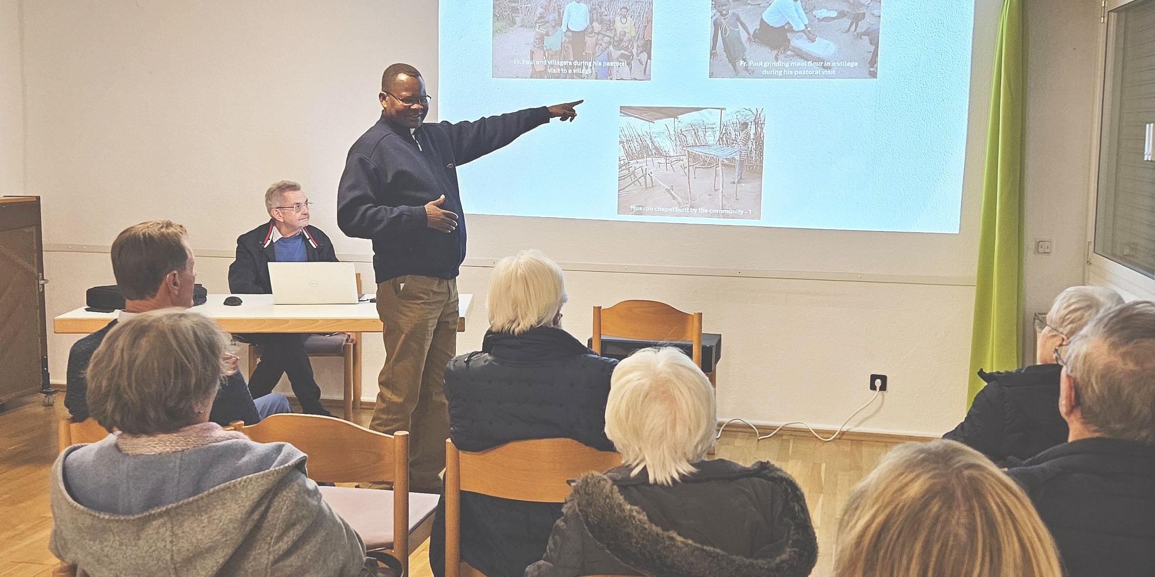 Generalvikar Ngole zeigt bei seinem Vortrag Bilder auf einer Leinwand.