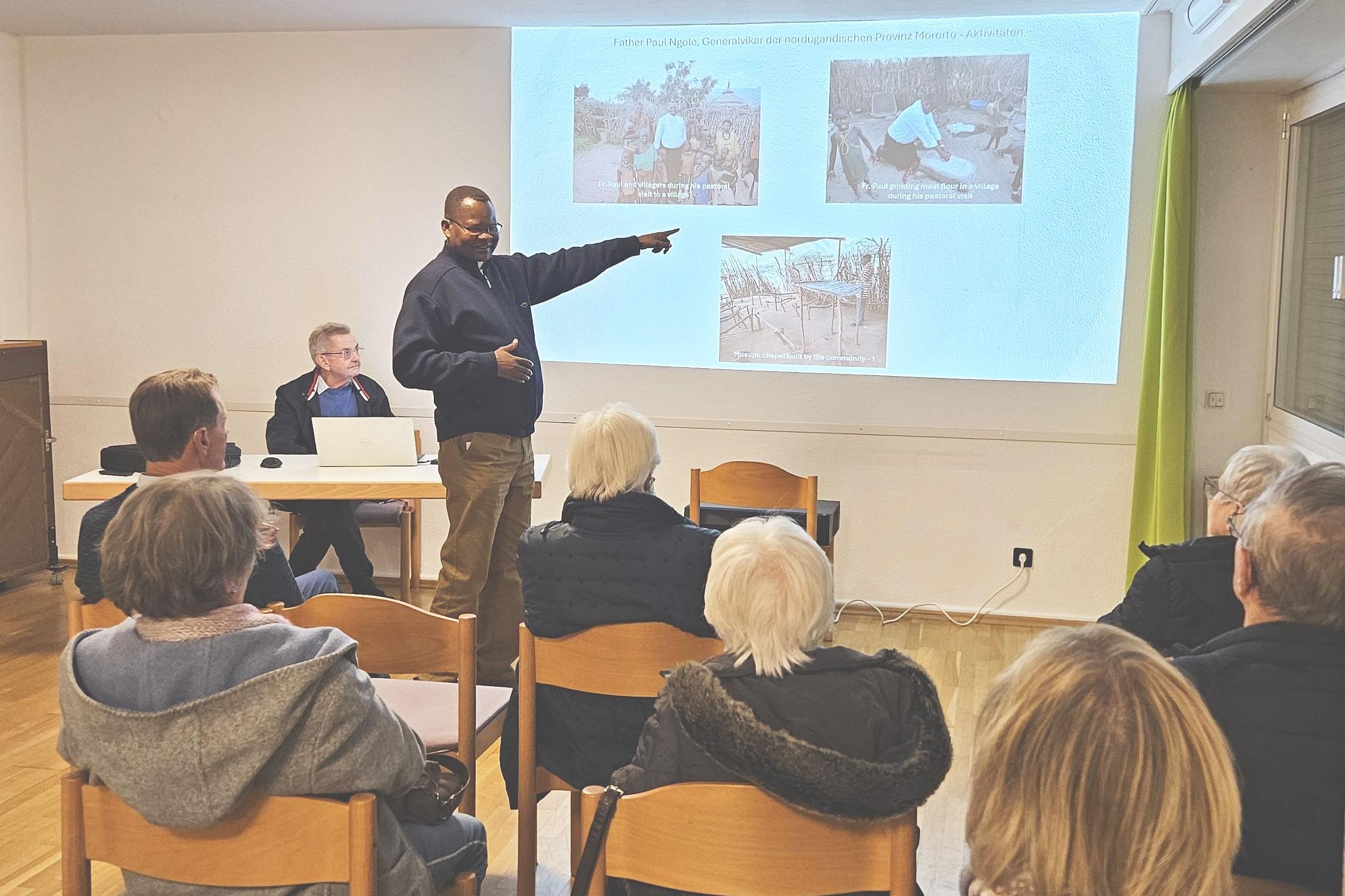 Generalvikar Ngole zeigt bei seinem Vortrag Bilder auf einer Leinwand.