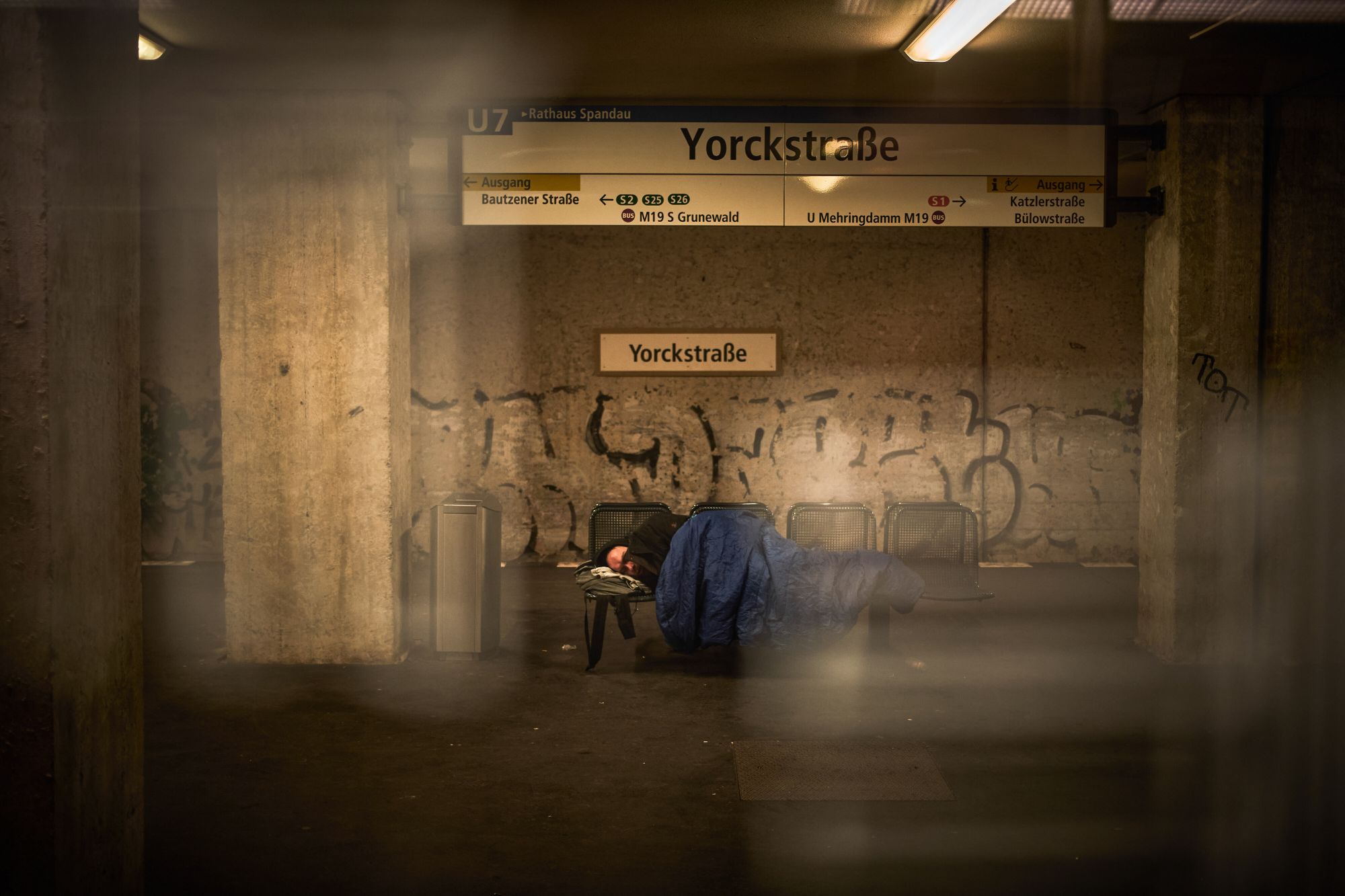 Ein Mensch liegt auf einer Bank in einer U-Bahn-Station