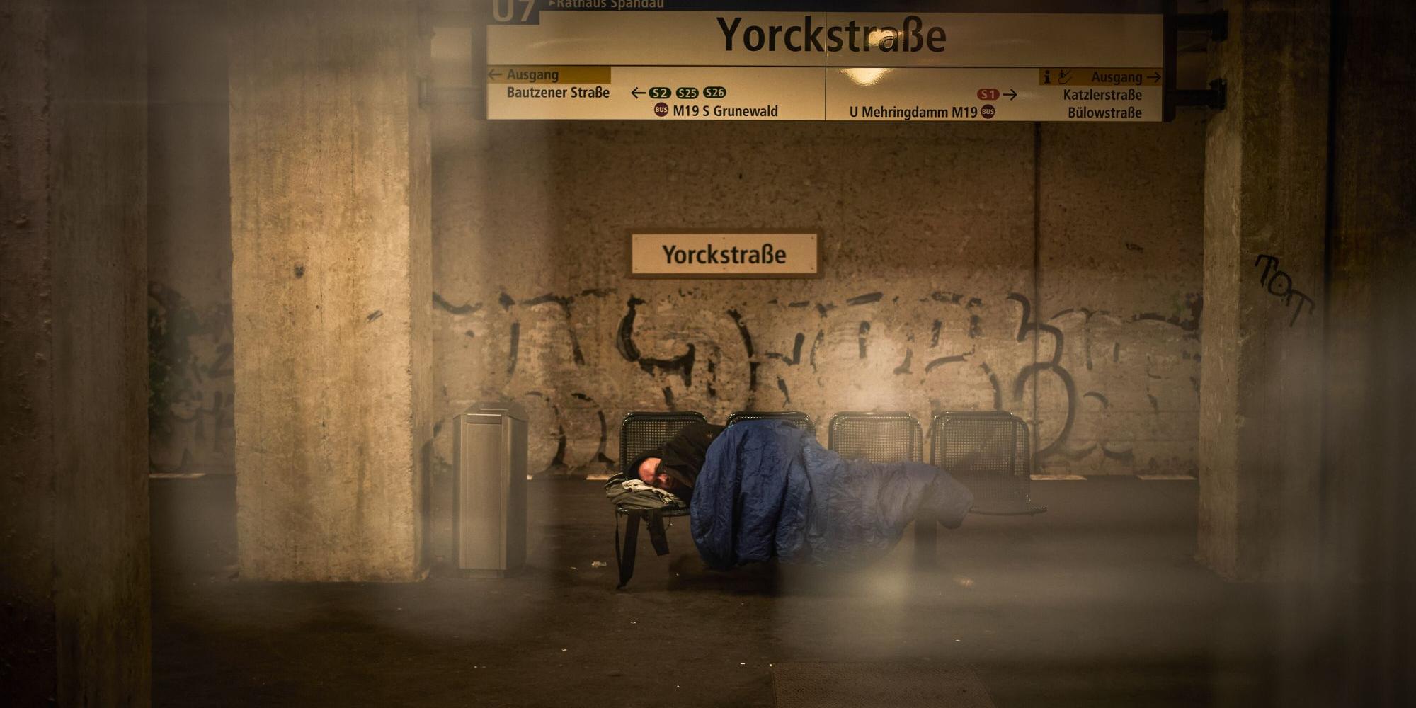 Ein Mensch liegt auf einer Bank in einer U-Bahn-Station