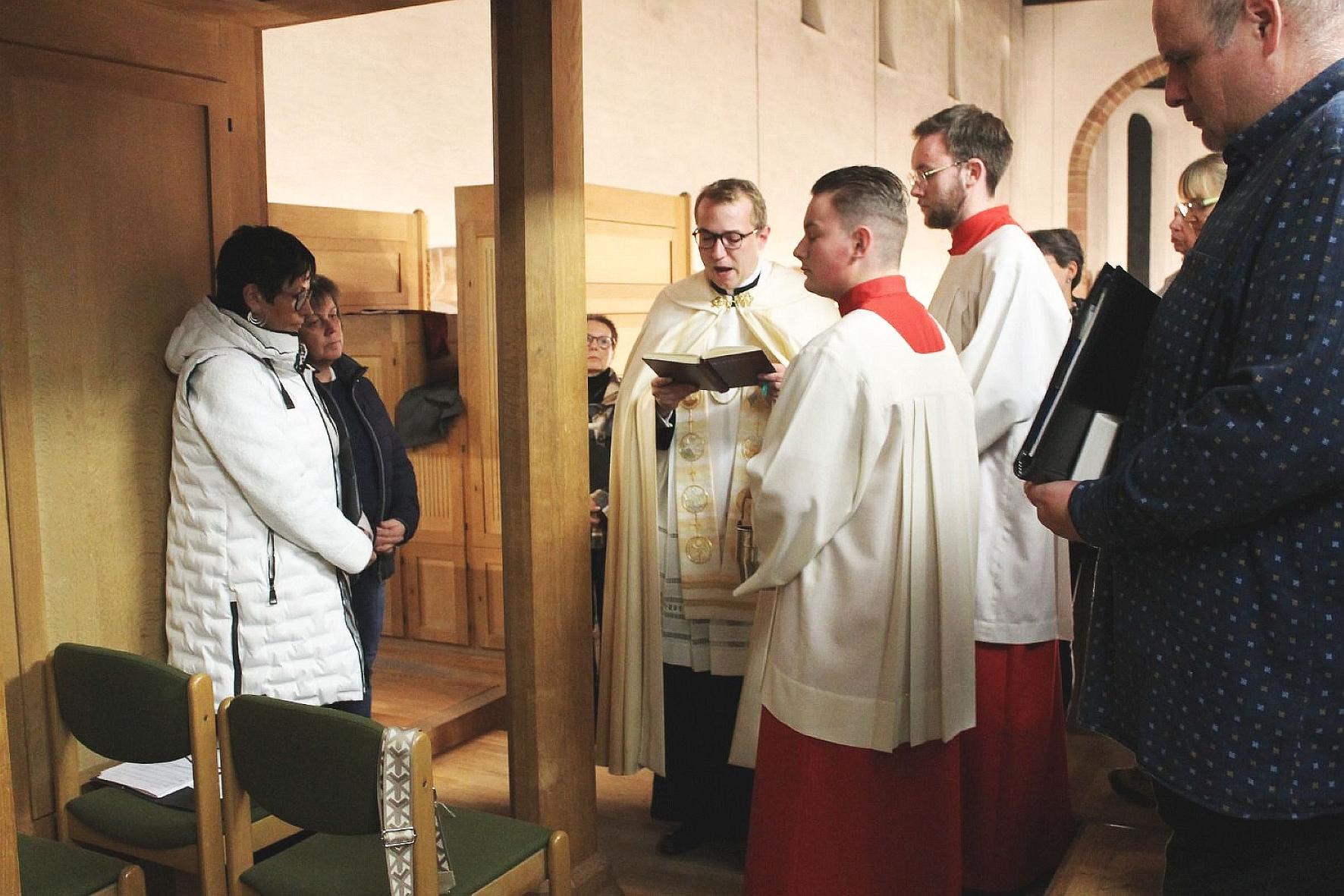Menschen stehen an einer Orgel, die von einem Priester gesegnet wird