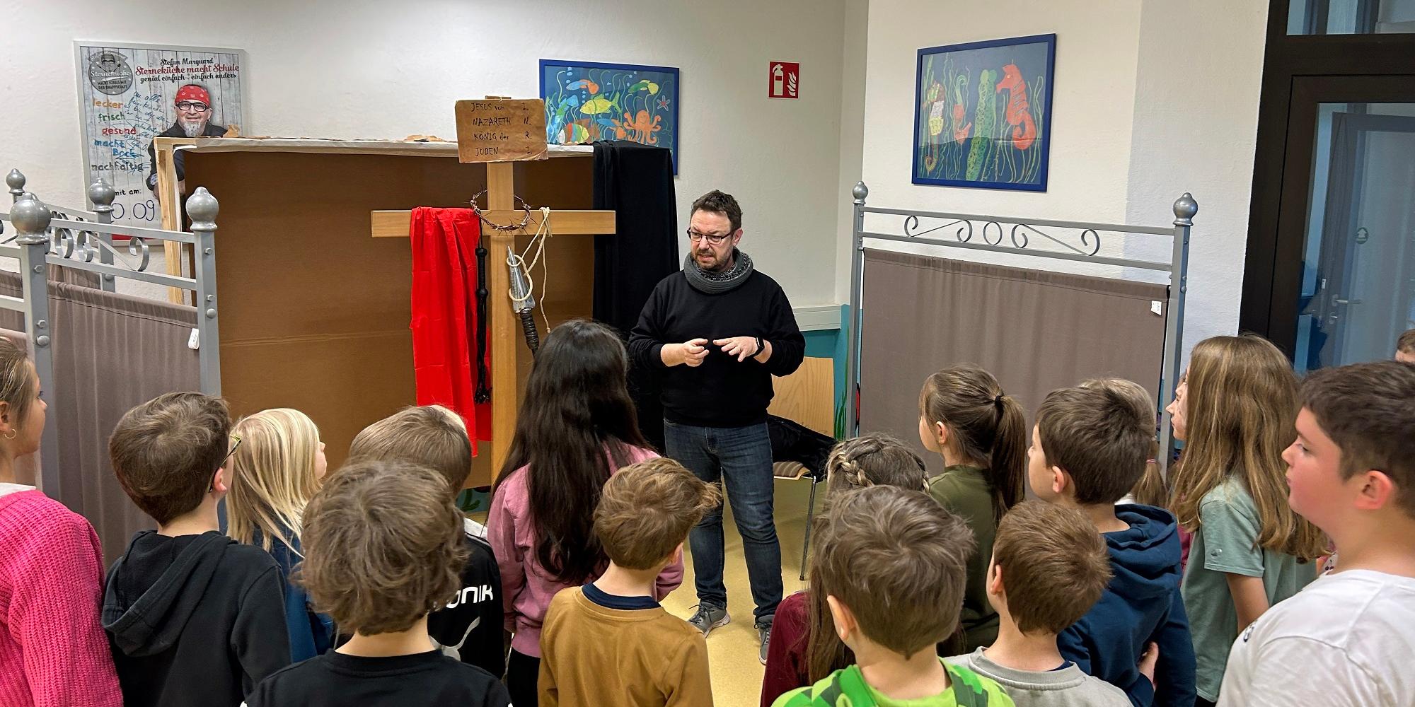 Gemeindereferent Peter Holz spricht mit der Klasse über die Kreuzigungsszene.