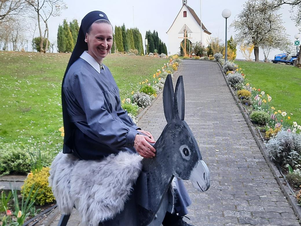 Eine Nonne sitzt auf einem Esel aus Holz