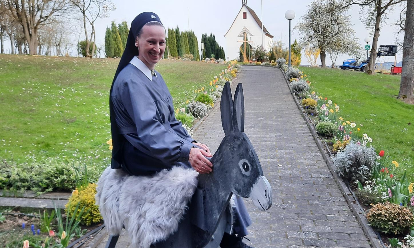 Eine Nonne sitzt auf einem Esel aus Holz