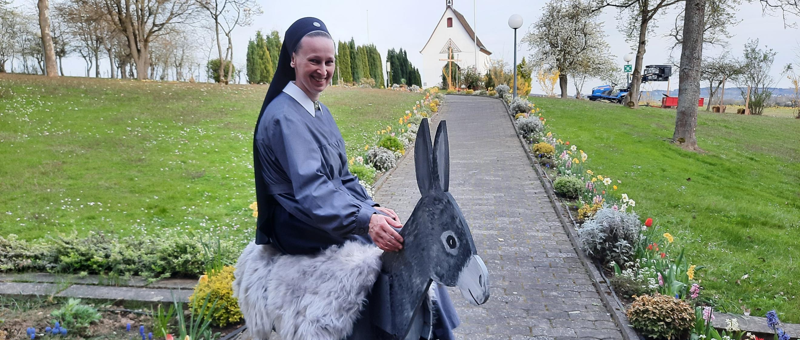 Eine Nonne sitzt auf einem Esel aus Holz