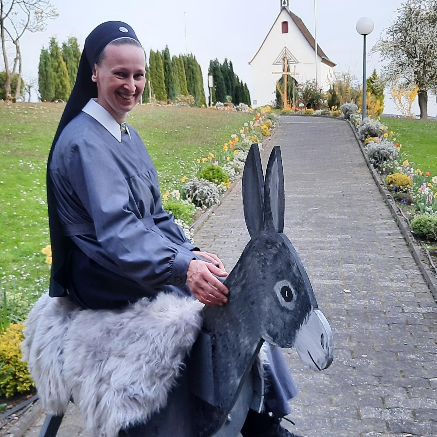 Eine Nonne sitzt auf einem Esel aus Holz