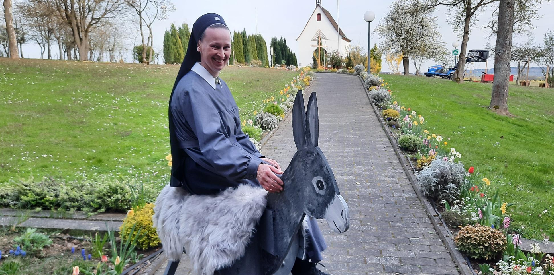 Eine Nonne sitzt auf einem Esel aus Holz