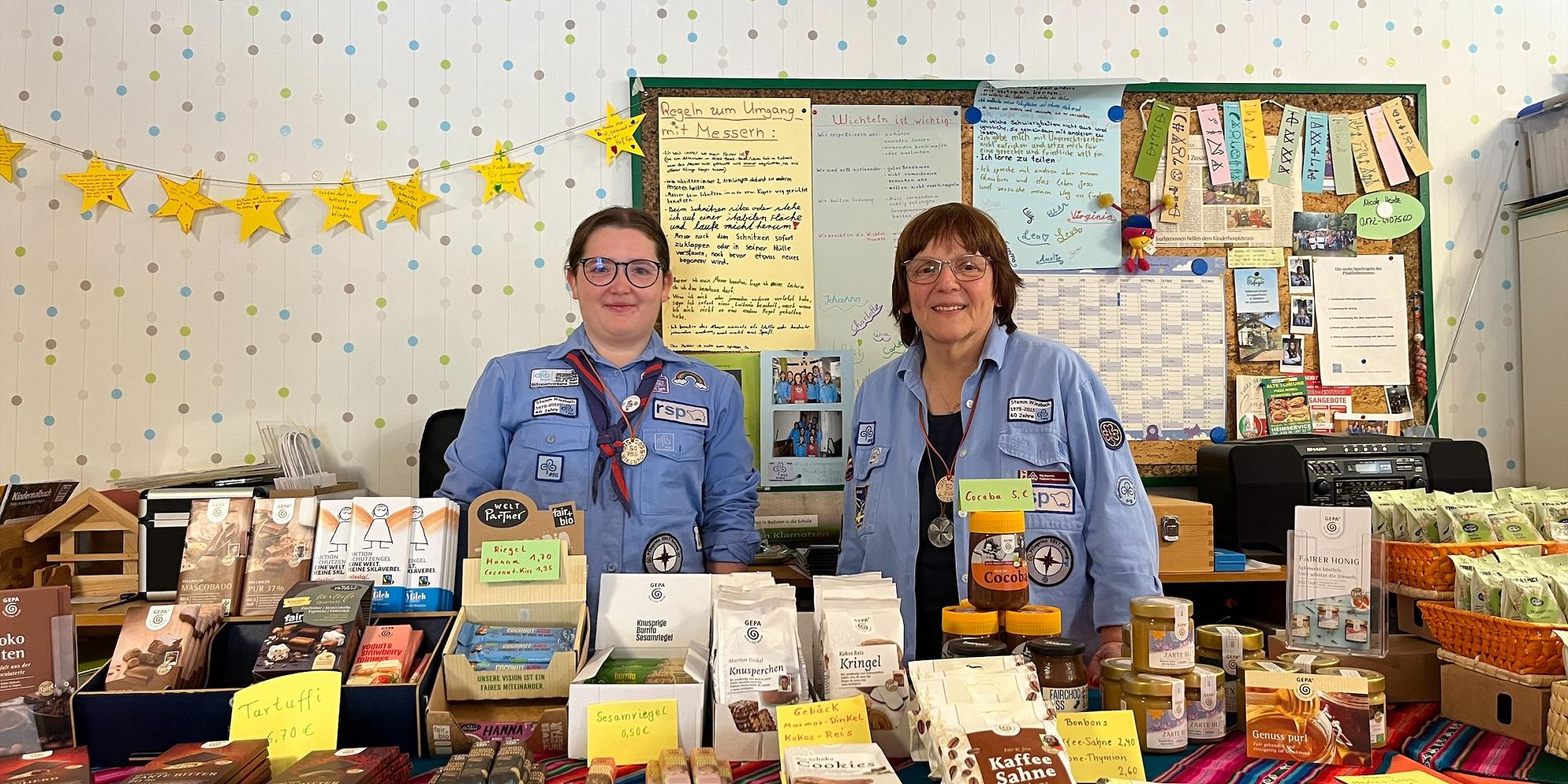 Zwei Pfadfinderinnen in Uniform an einem Verkaufstisch mit fair gehandelten Produkten. (c) Sarah Andre-Schött Zwei Pfadfinderinnen in Uniform an einem Verkaufstisch mit fair gehandelten Produkten.