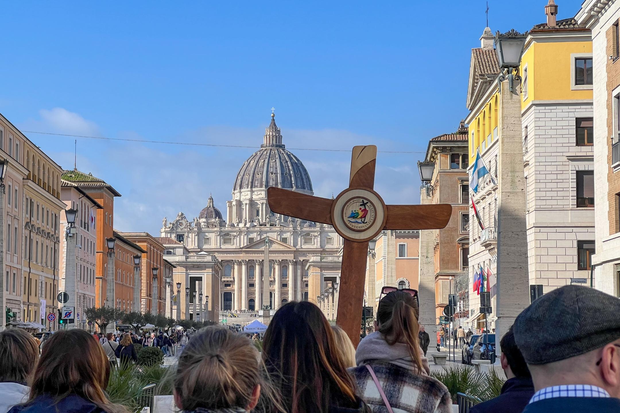 Eine deutsche Gruppe ist mit Pilgerkreuz unterwegs auf der Via della Conciliazione in Rom zum Petersdom.