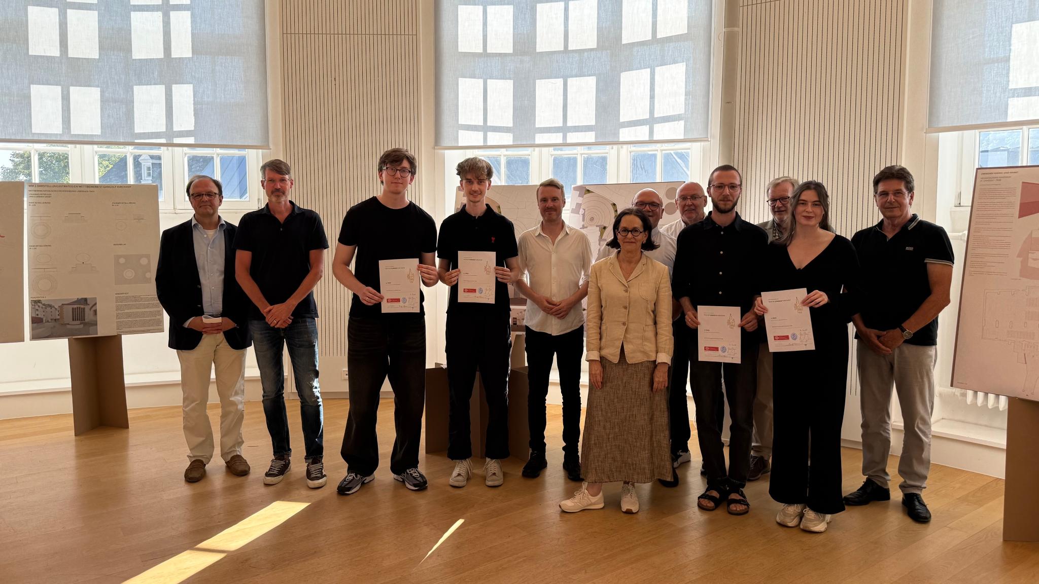 Mehrere Personen mit Urkunden in den Händen lachen in die Kamera