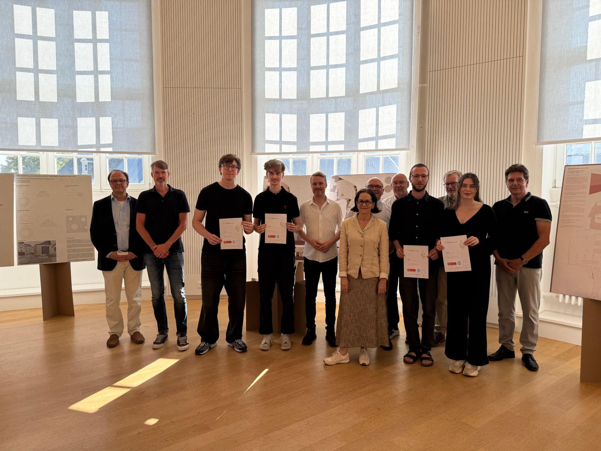 Mehrere Personen mit Urkunden in den Händen lachen in die Kamera