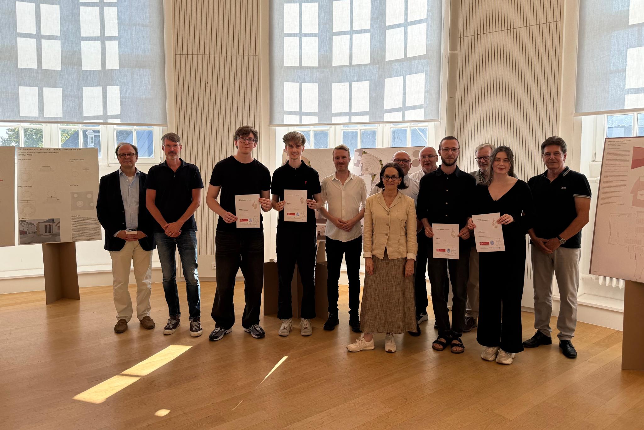 Mehrere Personen mit Urkunden in den Händen lachen in die Kamera