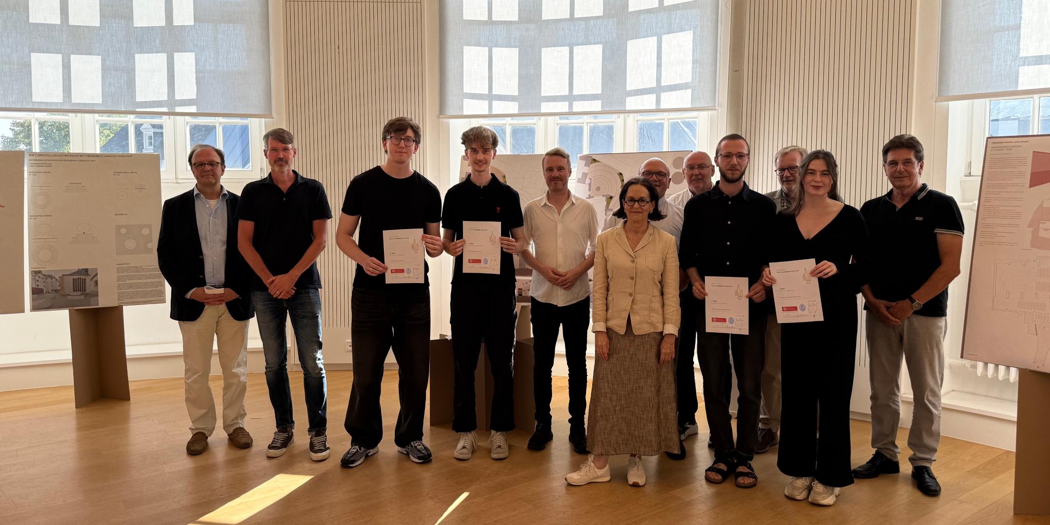 Mehrere Personen mit Urkunden in den Händen lachen in die Kamera