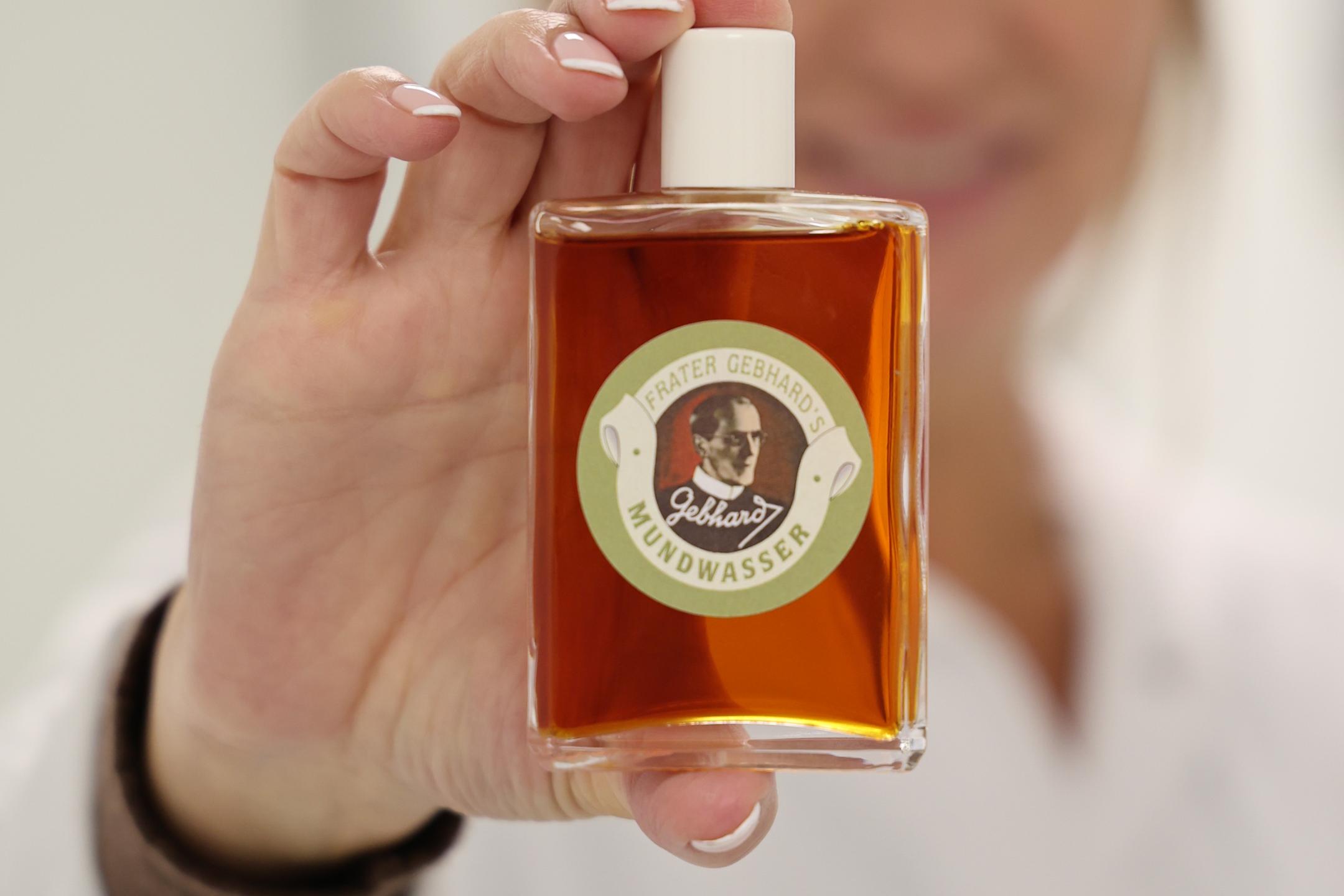 Eine Frau hält eine Flasche mit bräunlicher Flüssigkeit in die Kamera