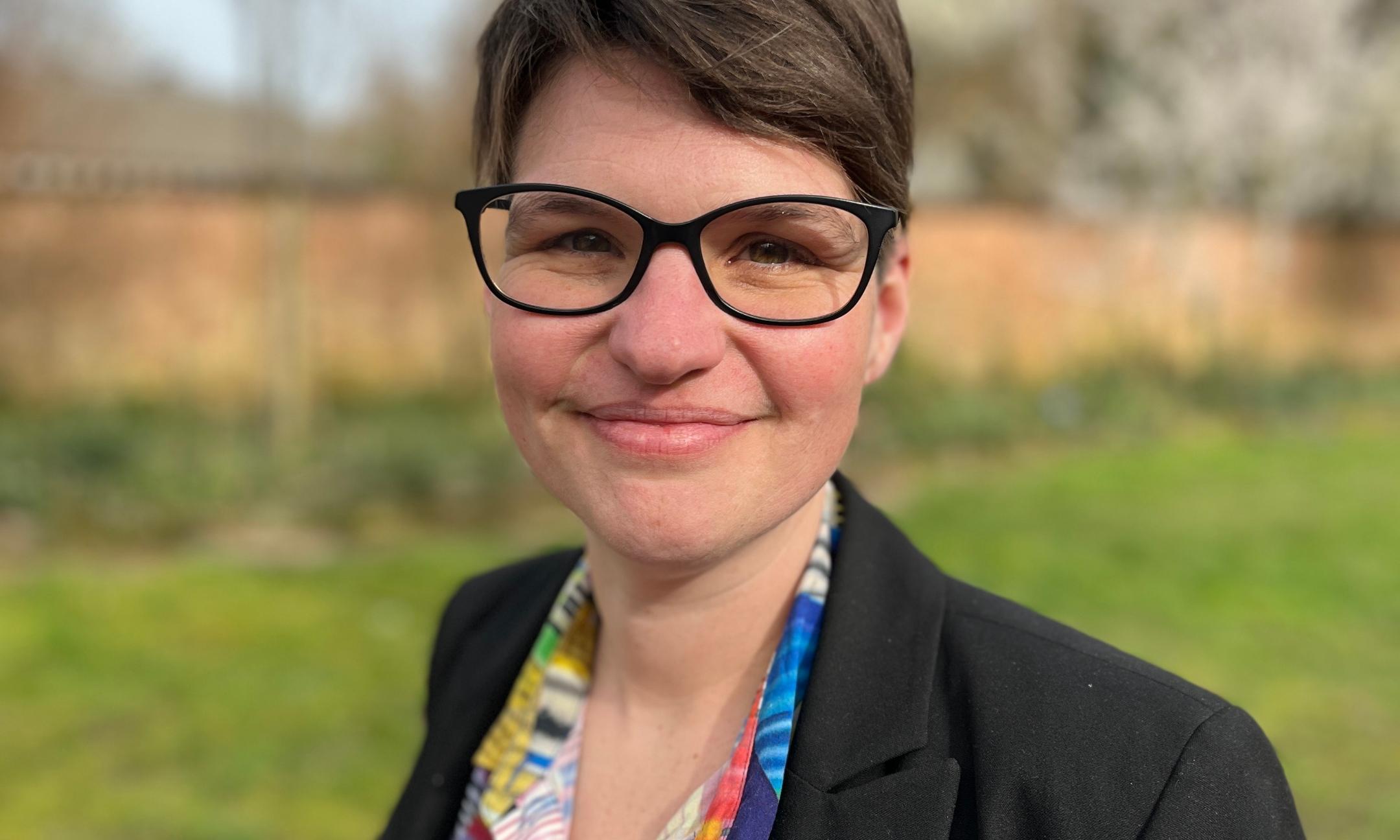 Eine Frau mit Brille lächelt in die Kamera