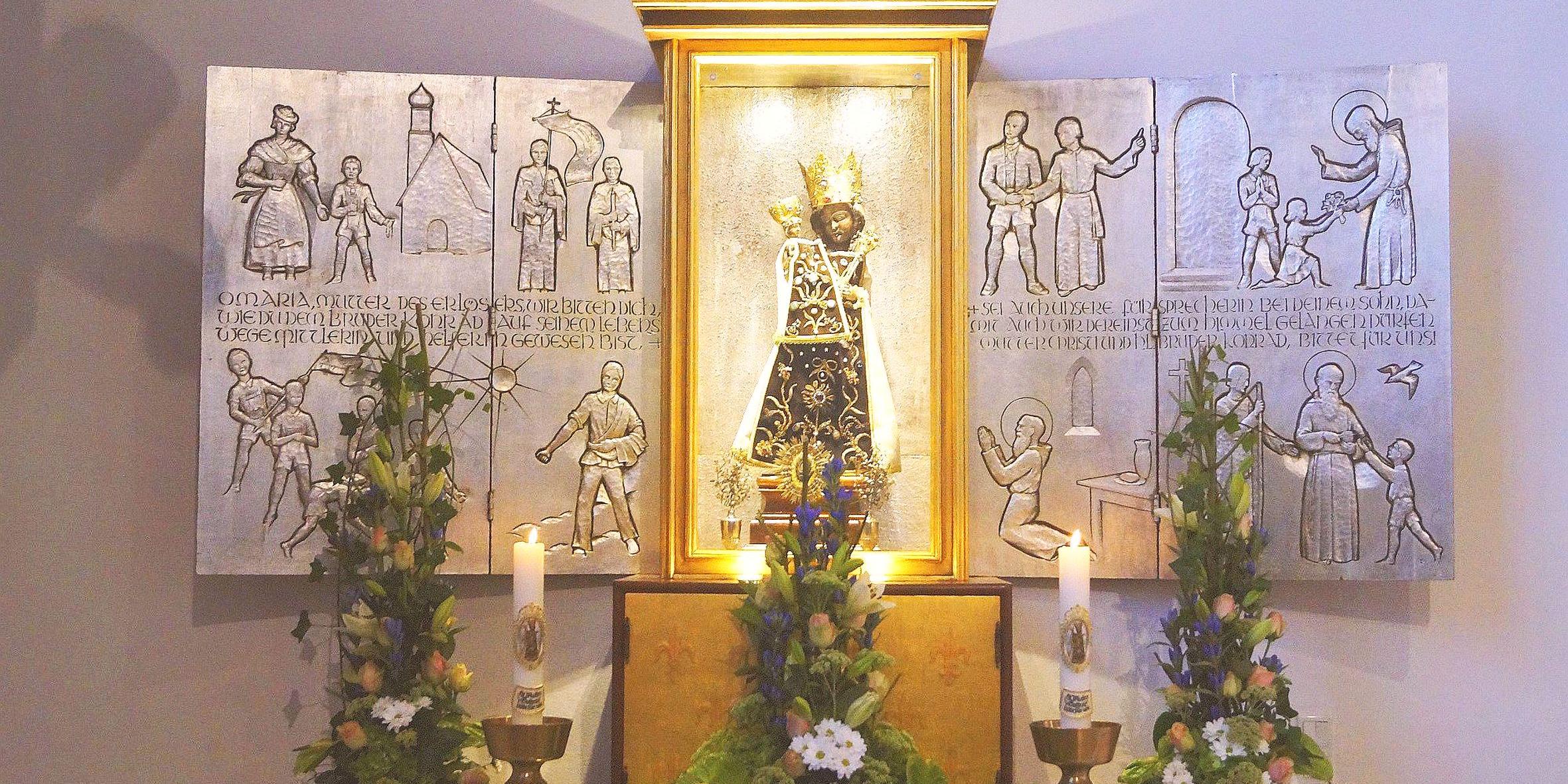 Das Gnadenbild der Schwarzen Madonna steht vor einem Altar mit Szenen aus dem Leben von Bruder Konrad.