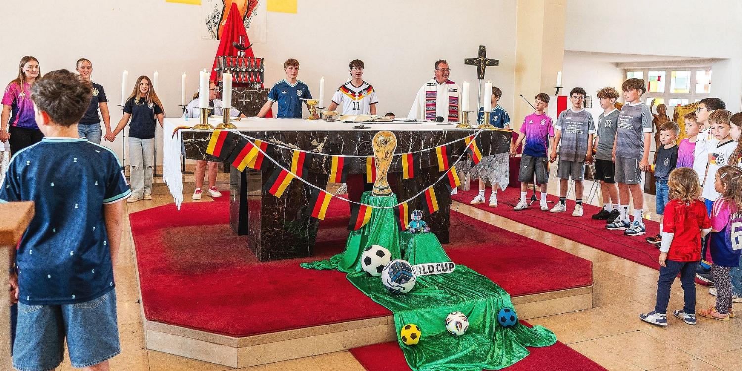 Pfarrer Peter Leick steht gemeinsam mit in Fußball-Dress gekleideten Kindern und Jugendlichen um den passend zur WM geschmückten Altar. (c) Rolf Ruppenthal Pfarrer Peter Leick steht gemeinsam mit in Fußball-Dress gekleideten Kindern und Jugendlichen um den passend zur WM geschmückten Altar.