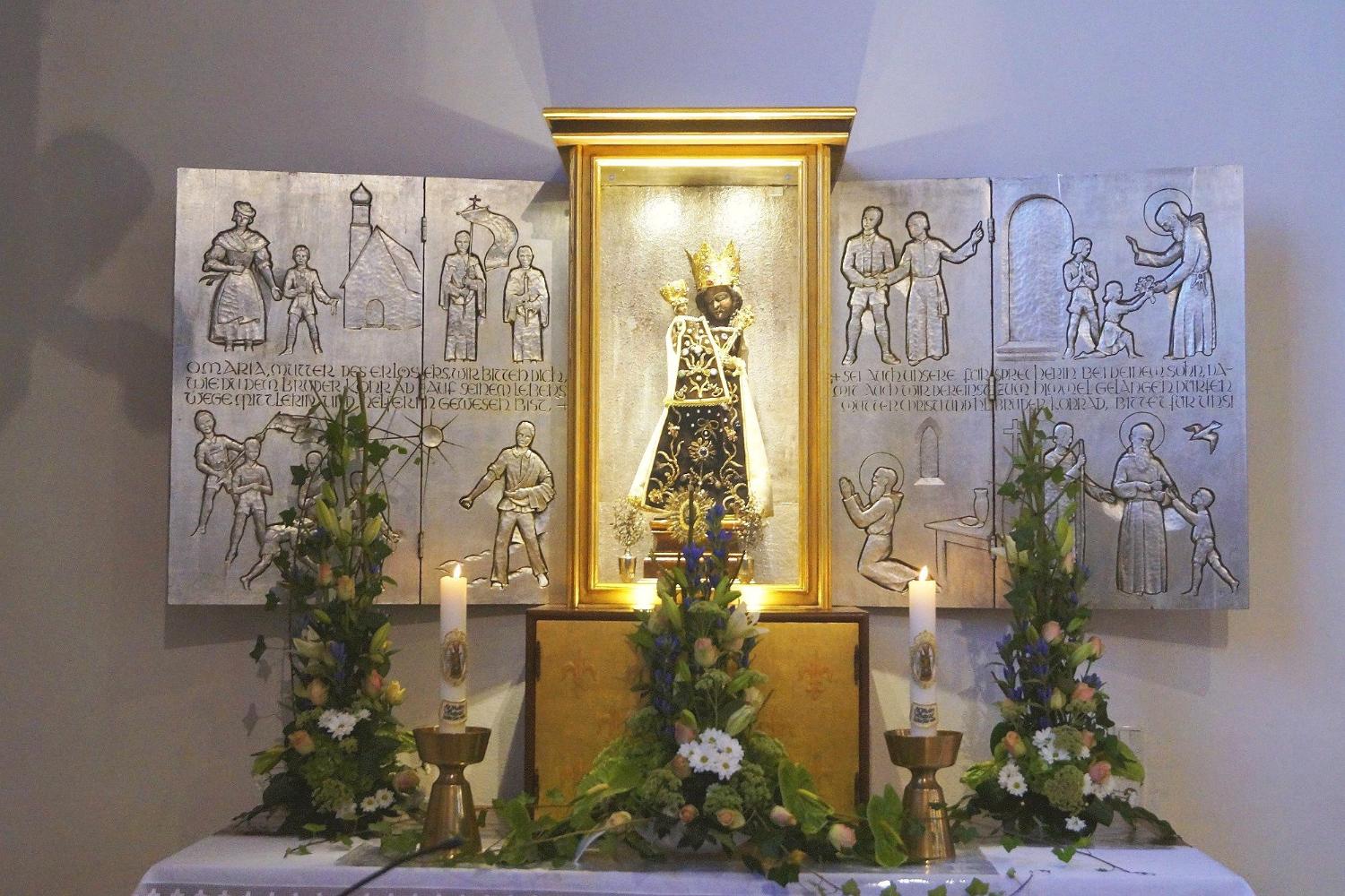 Das Gnadenbild der Schwarzen Madonna steht vor einem Flügelaltar aus der Kunstwerkstatt von Johann Mettler aus Morbach. Der Altar zeigt Szenen aus dem Leben des heiligen Bruder Konrad, Pförtner im Kloster Altötting.