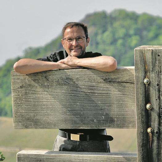 Der Pfarrer und Buchautor Jörg Meyrer stützt sich auf einer Holzkonstruktion ab.