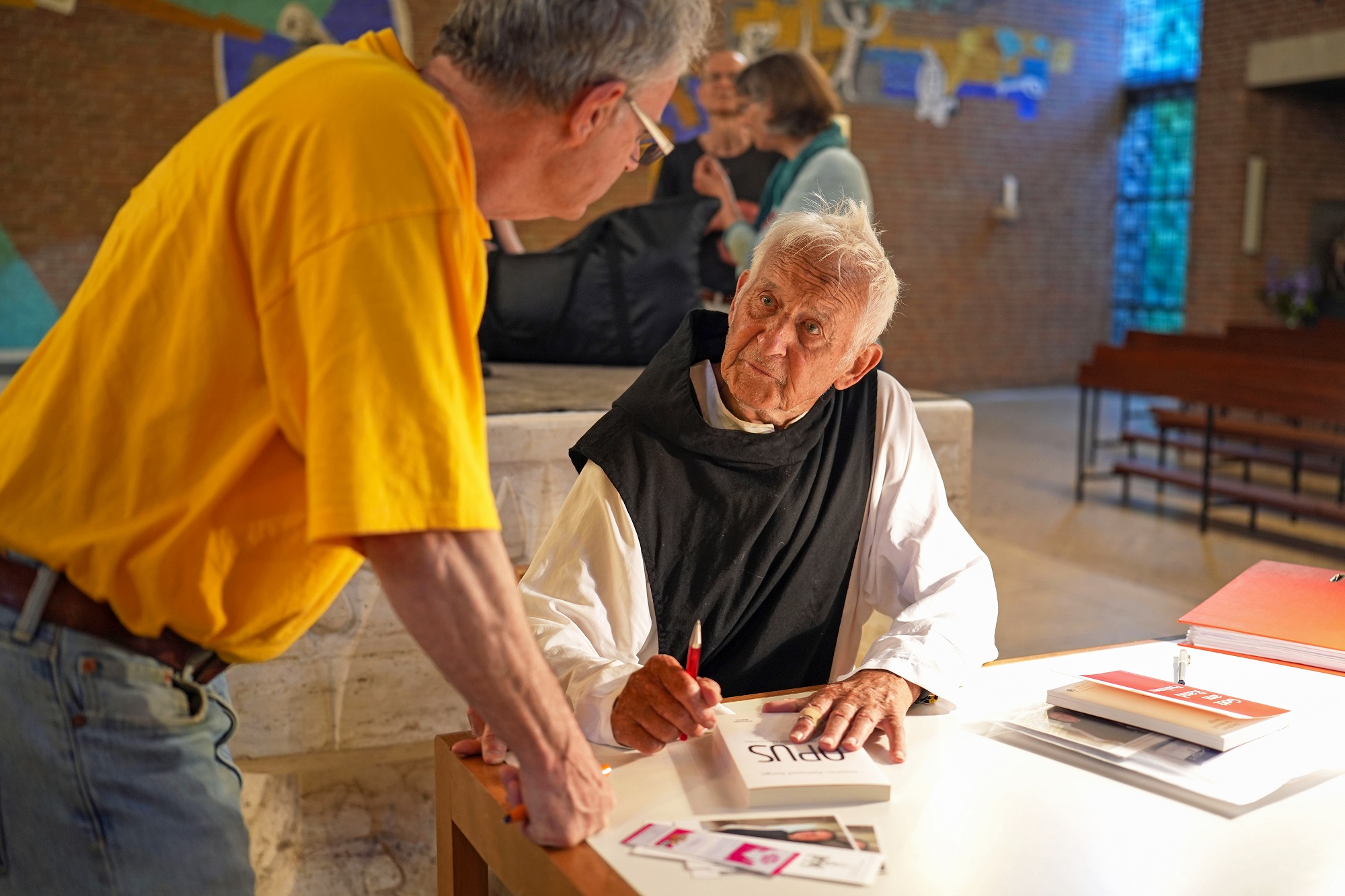 Pater Stephan signiert sein neuestes Buch mit dem Titel „Opus“.