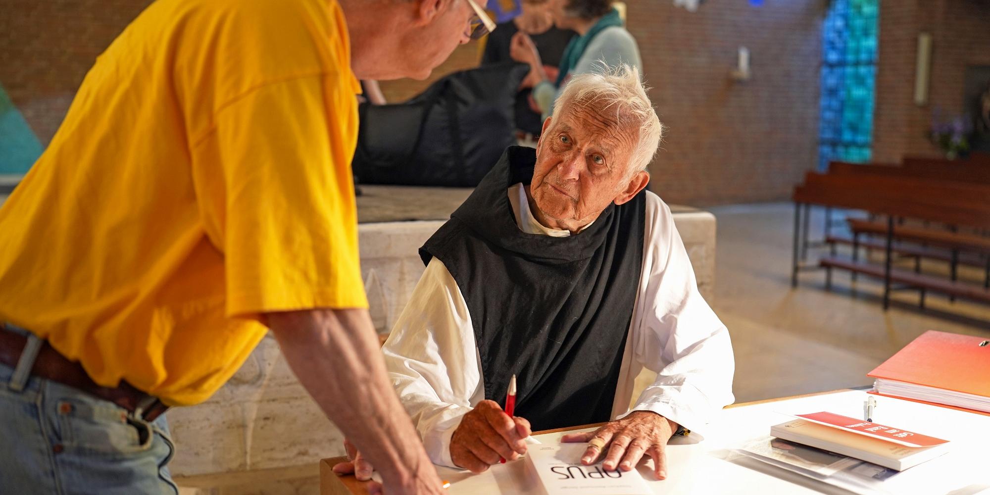Pater Stephan signiert sein neuestes Buch mit dem Titel „Opus“.