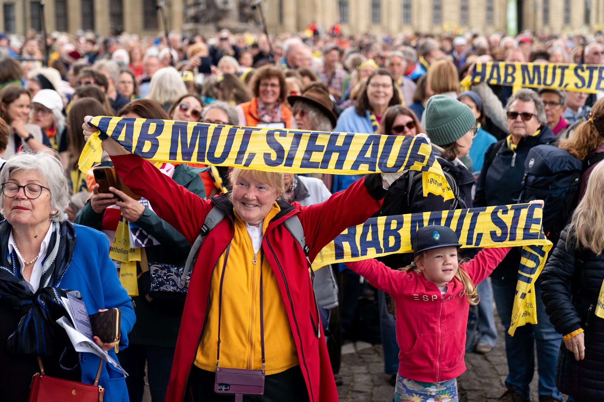 Teilnehmer halten Katholikentags-Schals hoch beim Abschlussgottesdienst am 17. Mai in Würzburg.