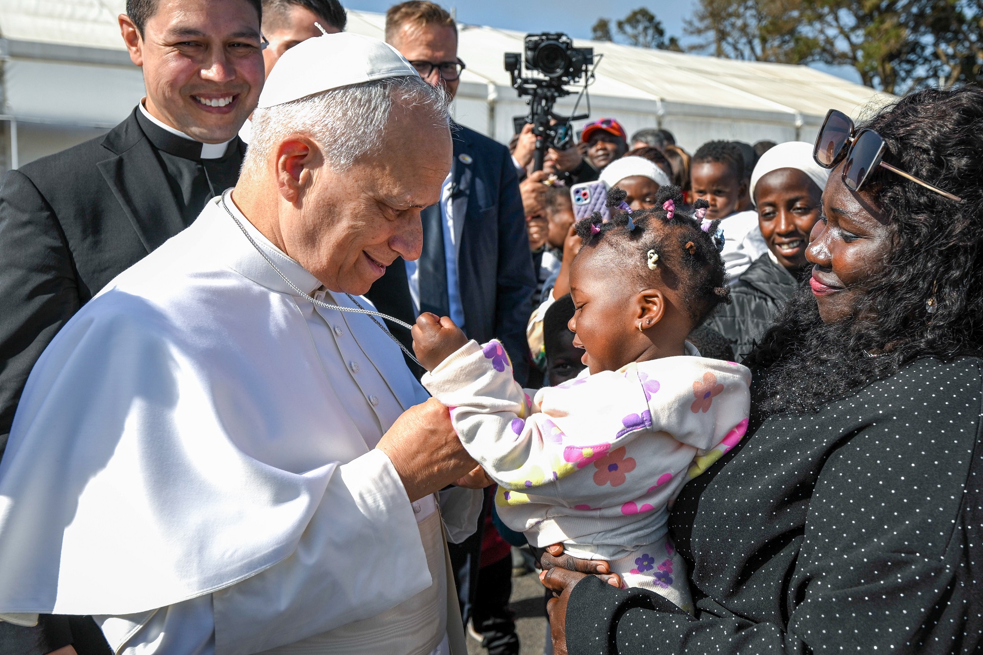 Ein Kleinkind auf dem Arm der Mutter und der Papst
