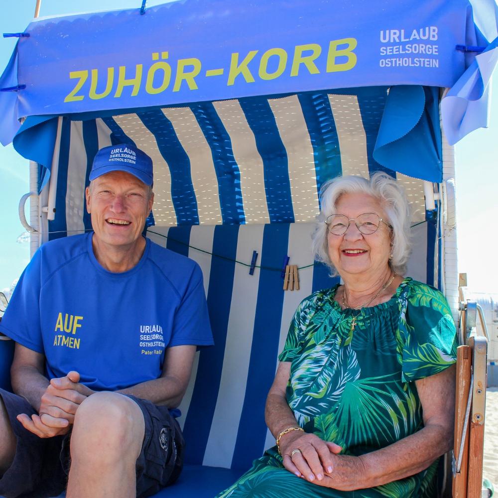 Urlauberseelsorger Pater Ralf Winterberg sitzt mit Touristin Anita Wendt im Ostseebad Dahme in einem „Zuhör-Korb“.