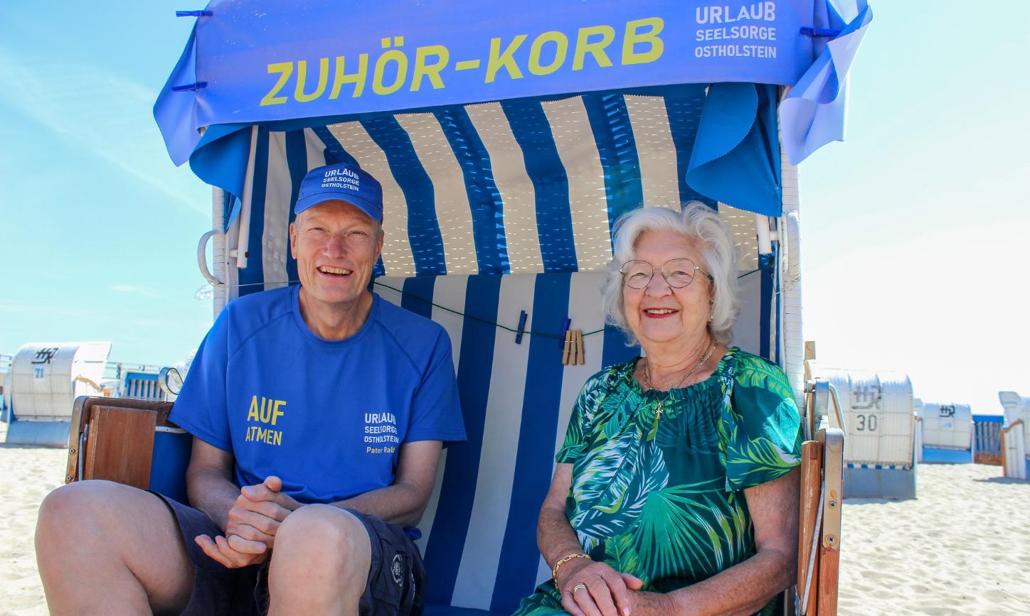 Urlauberseelsorger Pater Ralf Winterberg sitzt mit Touristin Anita Wendt im Ostseebad Dahme in einem „Zuhör-Korb“.