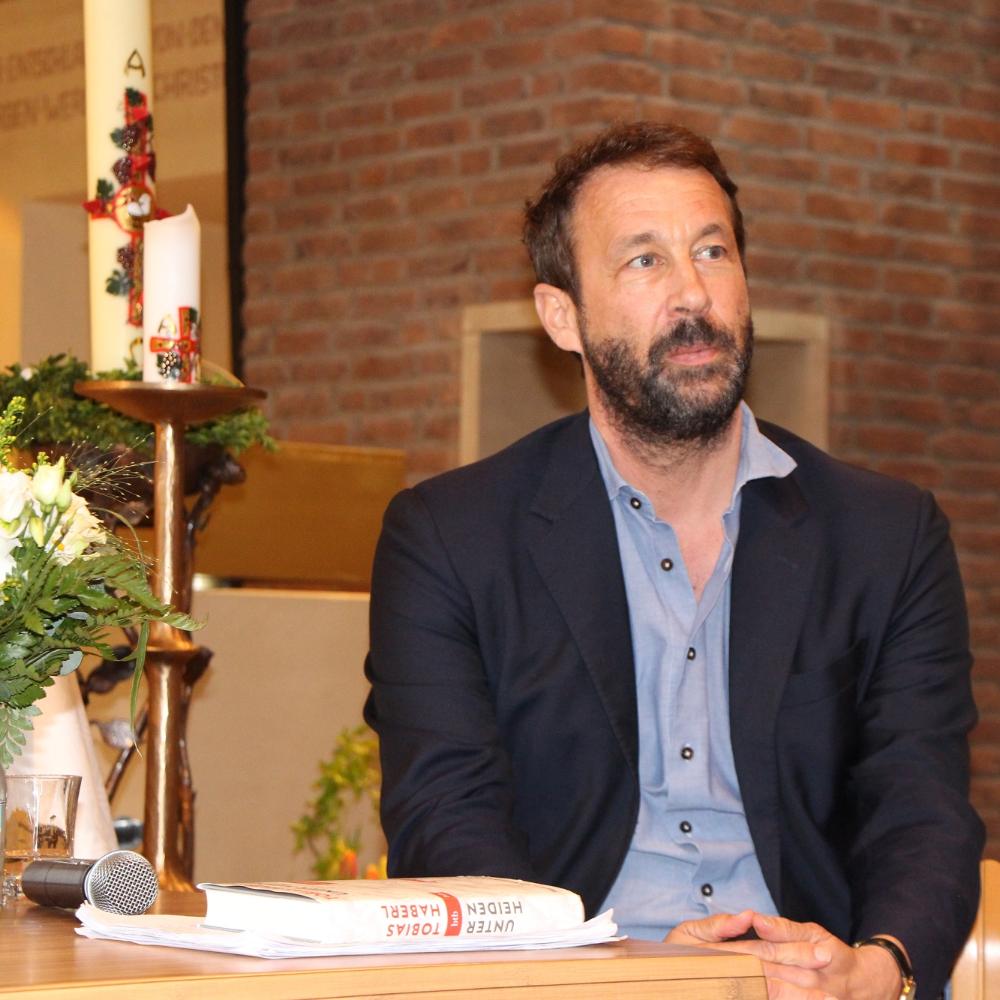 Bestsellerautor Tobias Haberl sitzt an einem Tisch in der Wallfahrtskirche des Klosters Maria Martental.