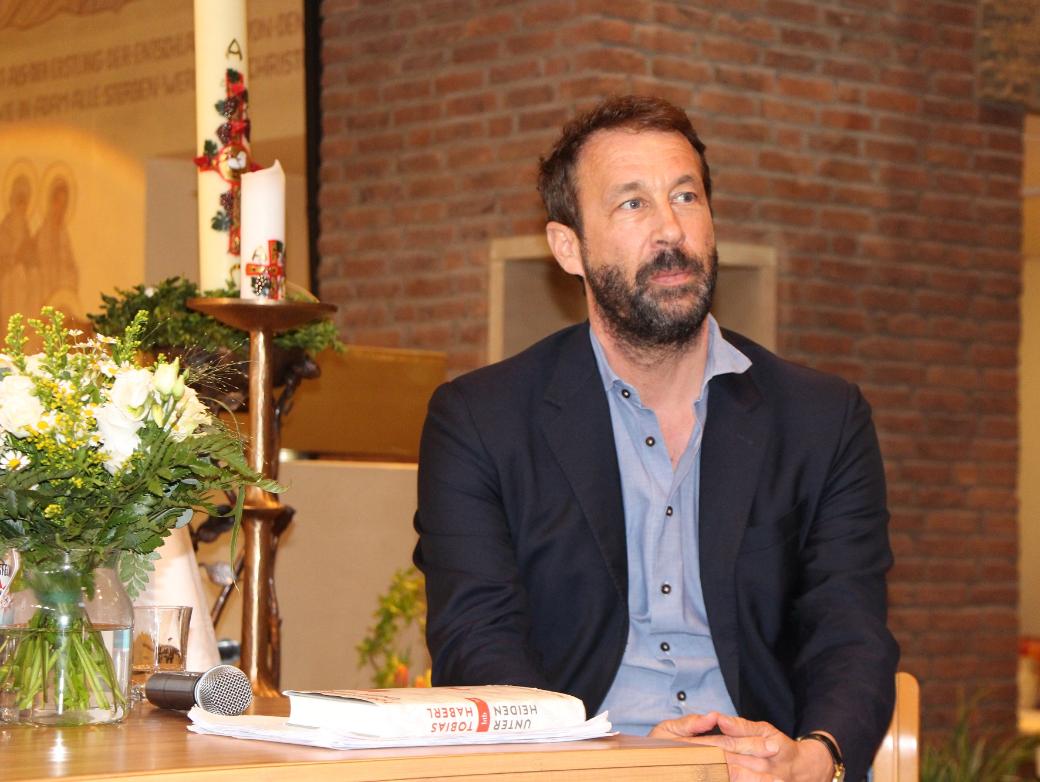 Bestsellerautor Tobias Haberl sitzt an einem Tisch in der Wallfahrtskirche des Klosters Maria Martental.