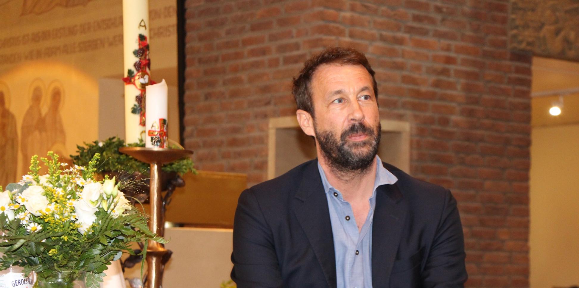 Bestsellerautor Tobias Haberl sitzt an einem Tisch in der Wallfahrtskirche des Klosters Maria Martental.