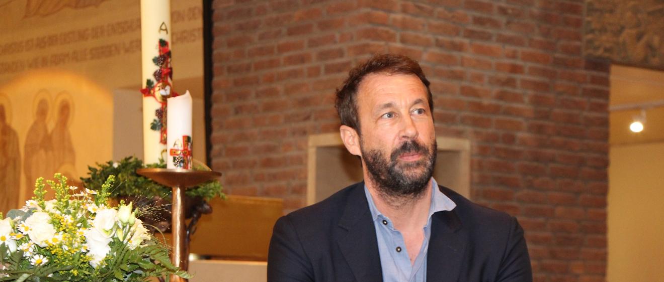 Bestsellerautor Tobias Haberl sitzt an einem Tisch in der Wallfahrtskirche des Klosters Maria Martental.