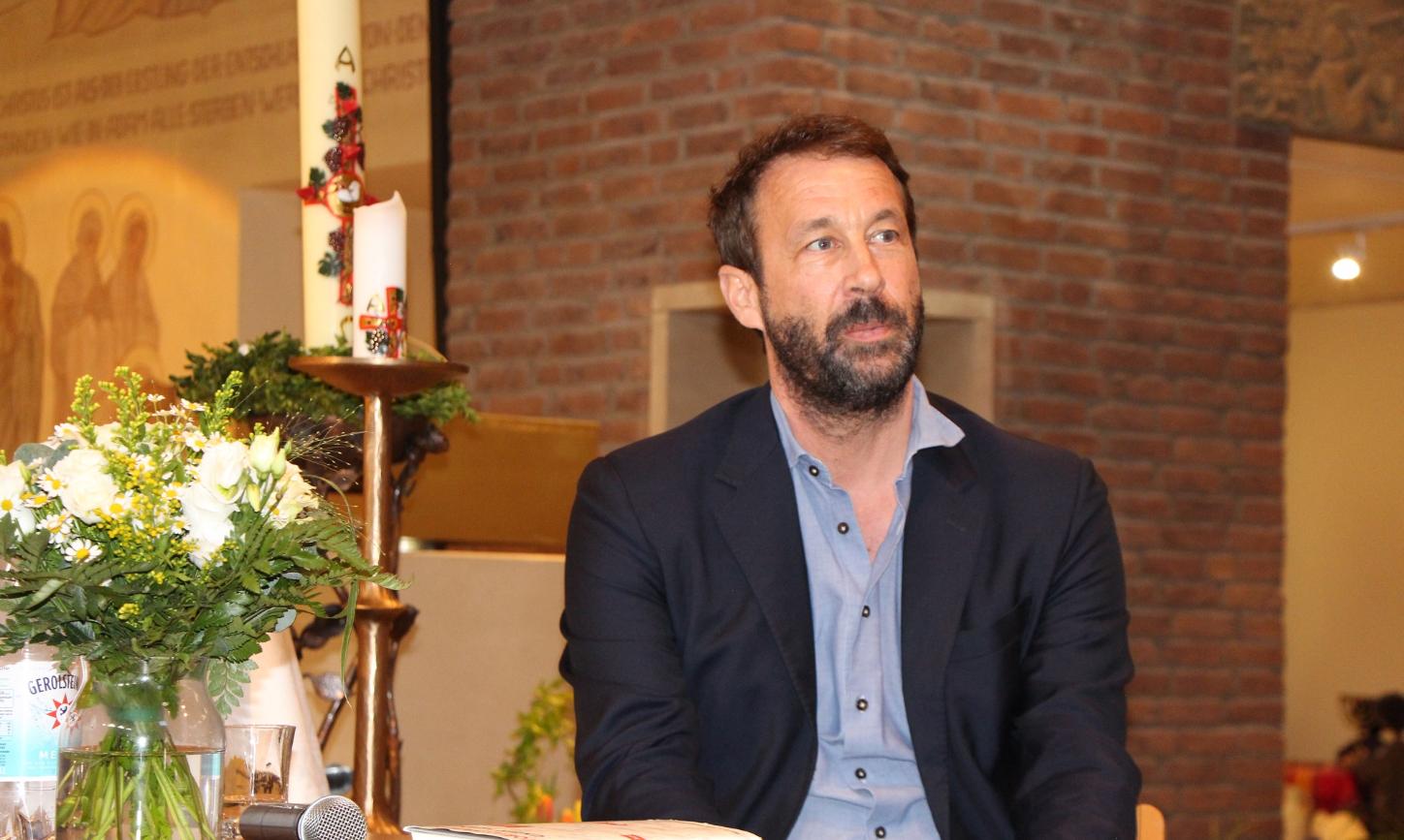 Bestsellerautor Tobias Haberl sitzt an einem Tisch in der Wallfahrtskirche des Klosters Maria Martental.
